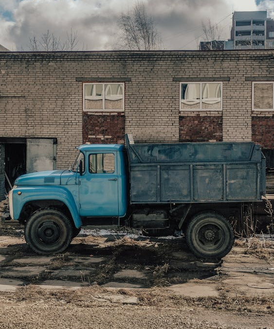 A blue dumpster parked outside a brown building