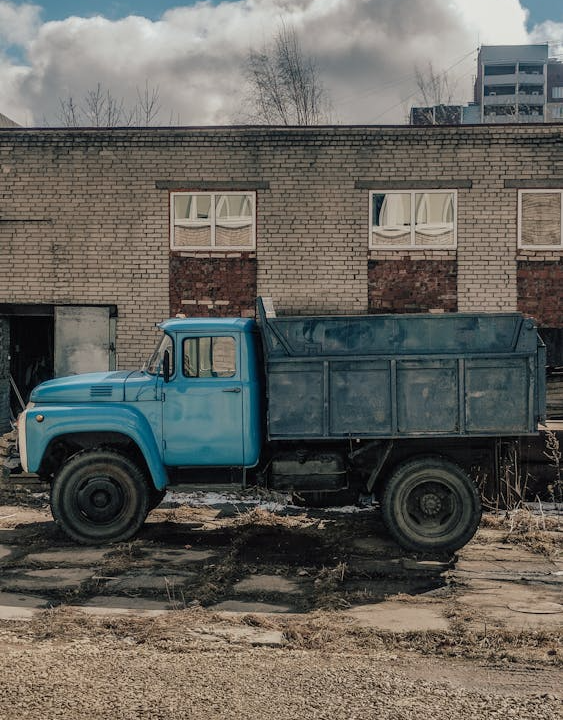 A blue dumpster parked outside a brown building