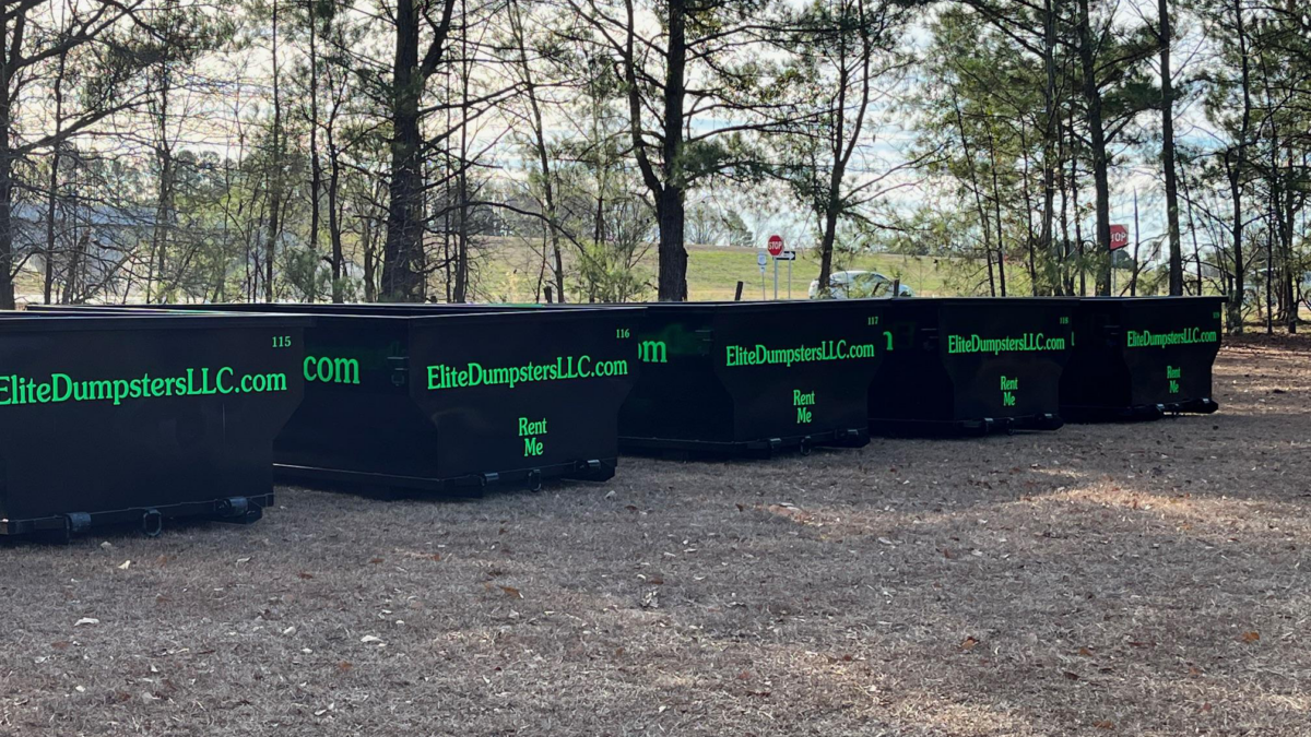 Multiple dumpsters in front of trees