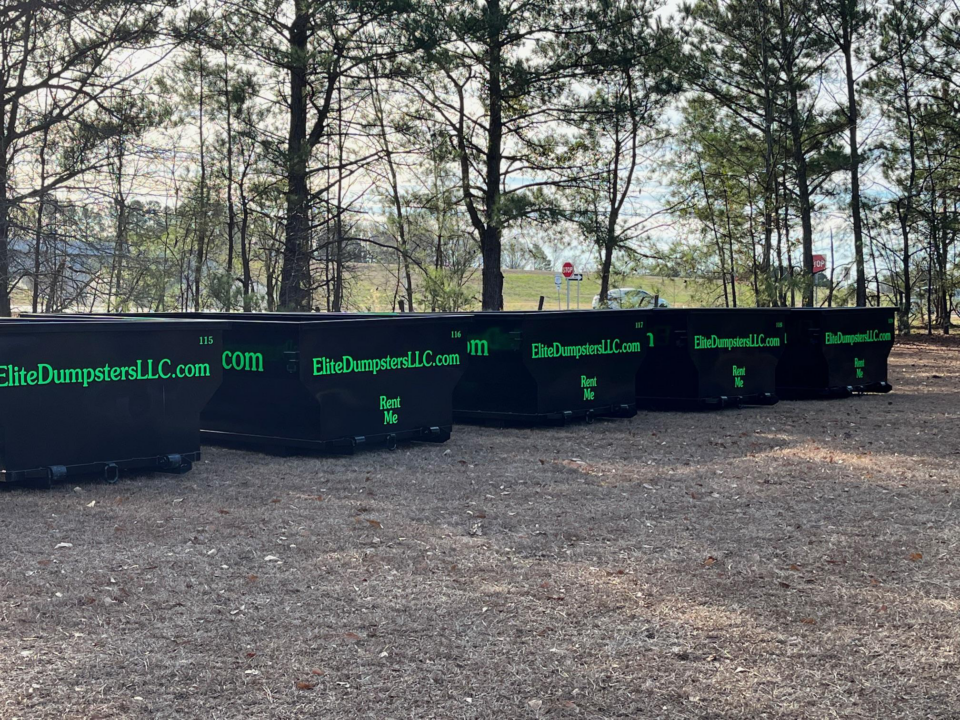 Multiple dumpsters in front of trees