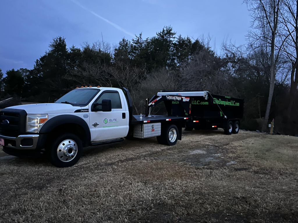 A dumpster truck in front of trees