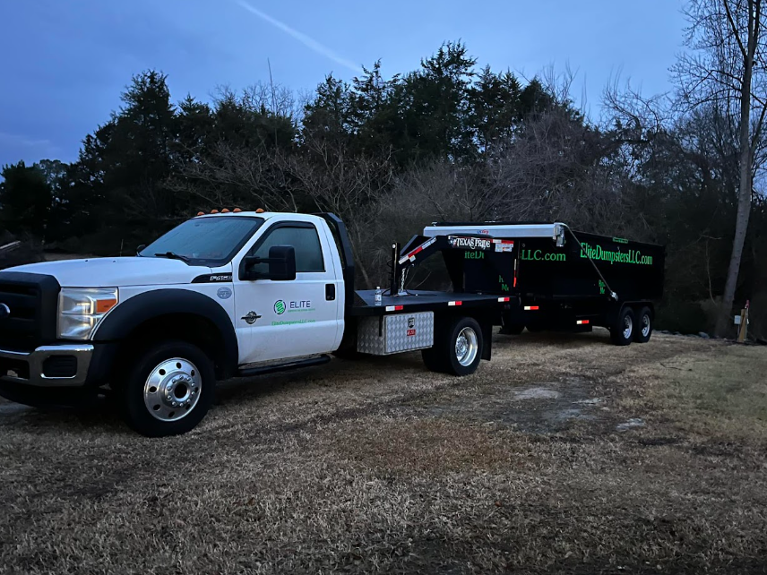 Roll-off truck arriving to transport a loaded dumpster, illustrating the final pickup stage after a cleanup or construction project is complete.