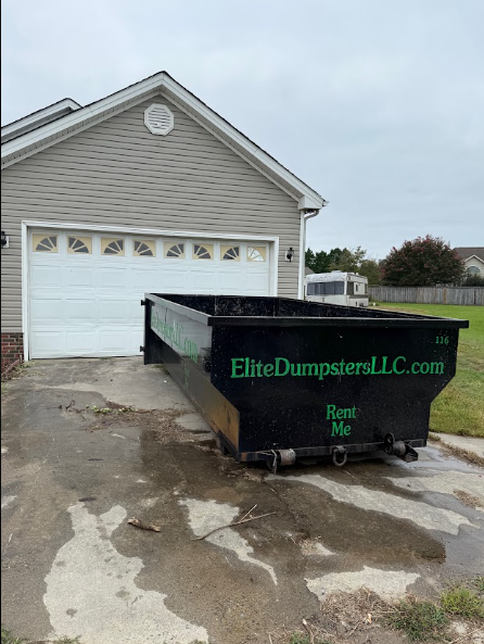 A dumpster in front of a garage 