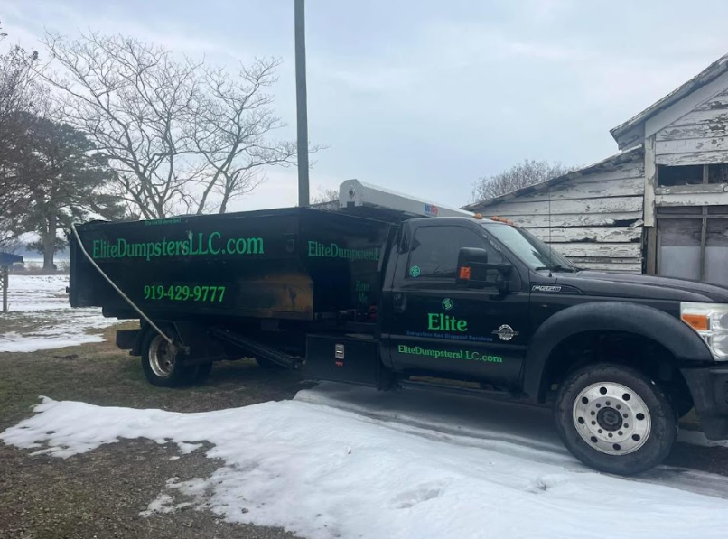 A black dumpster truck in front of a house