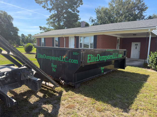 A dumpster on grass in front of a house 