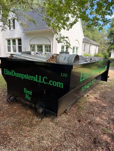 A dumpster outside of a house with white walls