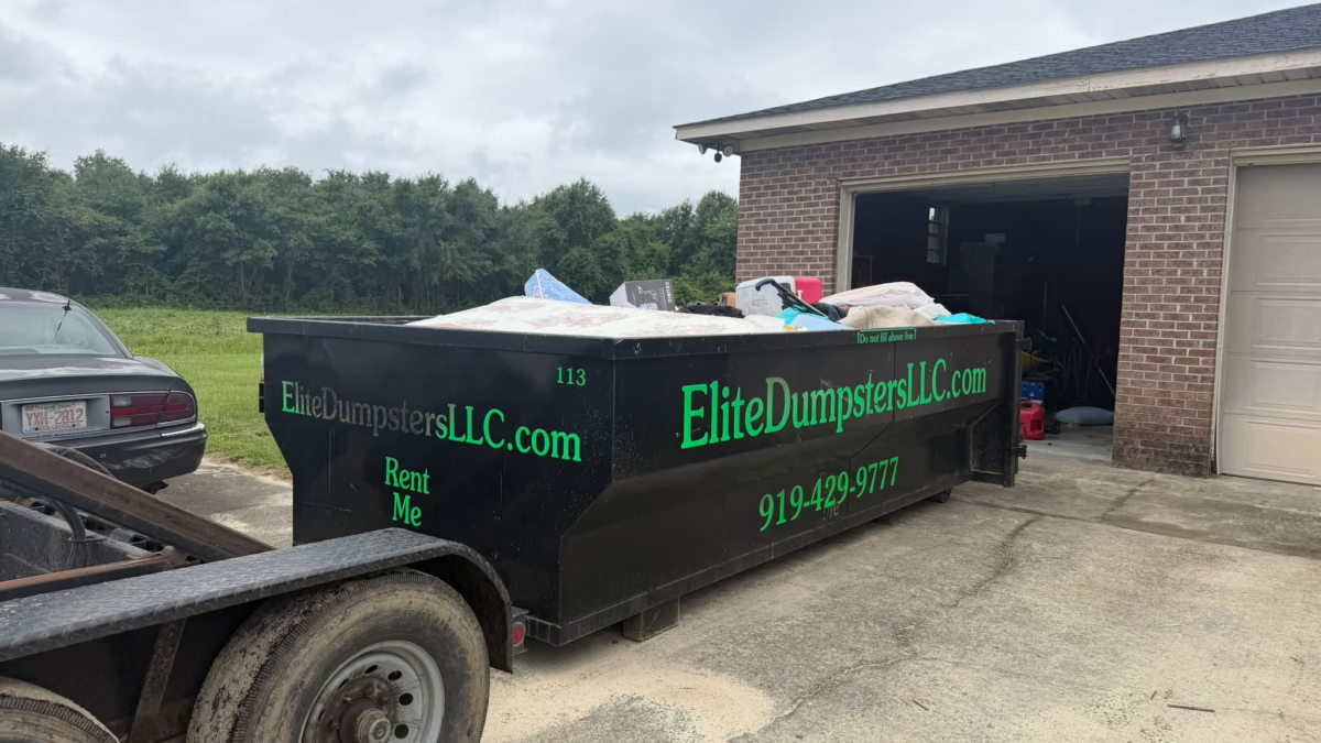 A dumpster in front of a garage