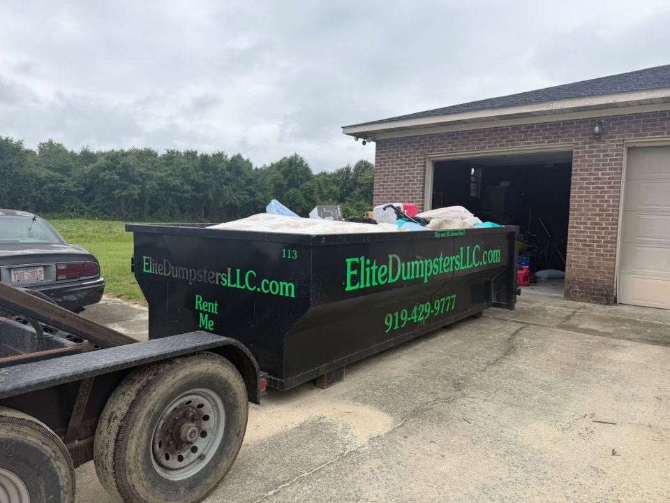 A dumpster in front of a garage