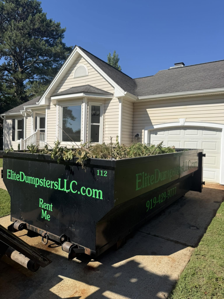 A dumpster with yard debris outside a house 